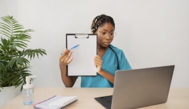 Free online health training concept—healthcare student attending virtual class with laptop, holding a clipboard, and taking notes at home