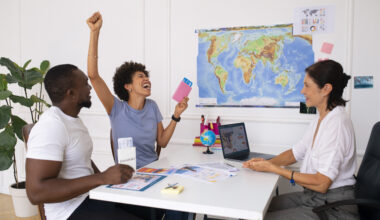 Apply Health Scholarships Successfully concept—excited students celebrating visa approval at a travel agency with passports, a world map, and study abroad planning documents.