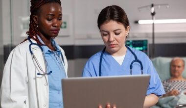 Healthcare professionals reviewing patient records on a laptop in a hospital, representing entry-level hospital jobs and healthcare career opportunities.