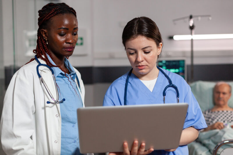 Healthcare professionals reviewing patient records on a laptop in a hospital, representing entry-level hospital jobs and healthcare career opportunities.