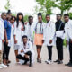 Group of diverse African medical students wearing white lab coats and stethoscopes, standing outdoors together, representing future doctors pursuing medical education and scholarship opportunities in 2026.
