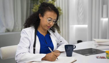 Healthcare professional writing patient notes at a desk, illustrating health careers without a degree, and medical administrative roles.