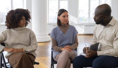 A mental health career professional leading a group therapy session with clients